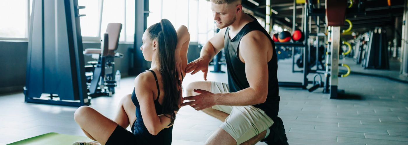 Gym therapy session with a male physiotherapy helping a woman with her fitness goals